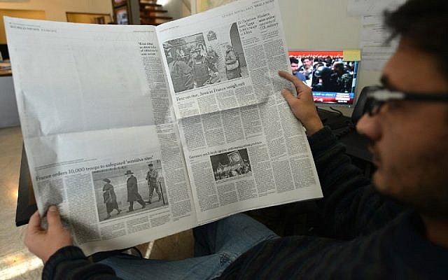 A Pakistani man reads a local edition of the International New York Times in Islamabad on January 14, 2015, which shows a blank section of a page that if printed, would report on the first issue of French satirical magazine Charlie Hebdo since a jihadist attack decimated its editorial staff last week. (photo credit: AFP/AAMIR QURESHI)