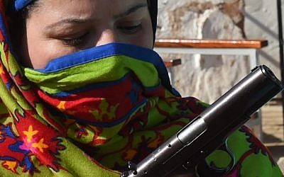 A Pakistani teacher loads a magazine into a pistol during a weapons training session for school, college and university teachers at a police training center in Peshawar on January 27, 2015. (photo credit: A Majeed/AFP)