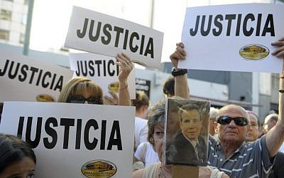 People hold placards that read "Justice" during a rally in front of the headquarters of the AMIA (Argentine Israelite Mutual Association), in Buenos Aires on January 21, 2015. (photo credit: Alejandro Pagni/AFP) 