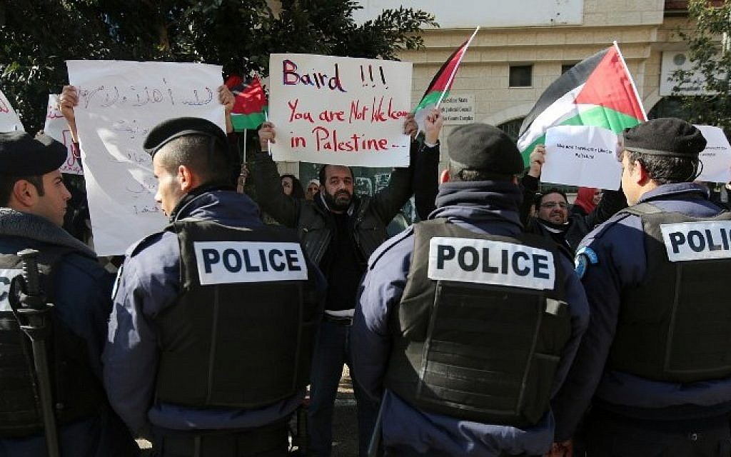 Policemen stand guard in front of Palestinian protesters holding placards before a meeting between Palestinian Authority Minister of Foreign Affairs Riyad al-Maliki and his Canadian counterpart John Baird on January 18, 2015, Ramallah. (AFP/ABBAS MOMANI)