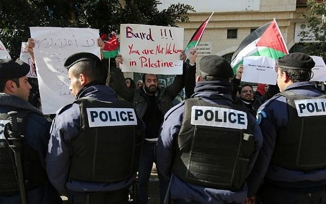 Policemen stand guard in front of Palestinian protesters holding placards before a meeting between Palestinian Authority Minister of Foreign Affairs Riyad al-Maliki and his Canadian counterpart John Baird on January 18, 2015, Ramallah. (AFP/ABBAS MOMANI) 