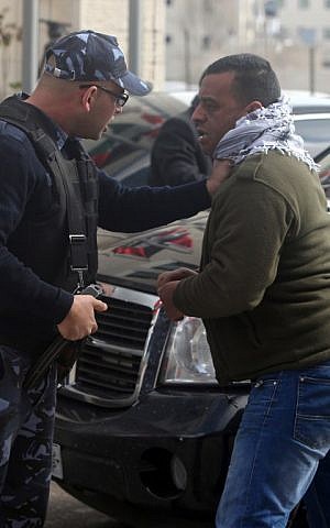 A Palestinian policeman stops a protester after angry Palestinian youths hurled eggs at the motorcade of Canadian Foreign Minister John Baird in Ramallah on Sunday, January 18, 2015 (photo credit: AFP/ABBAS MOMANI)