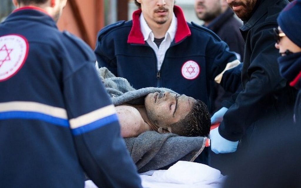 Medics transport a Palestinian man on a gurney who stabbed and wounded over a dozen passengers in an attack on a Tel Aviv bus on January 21, 2015 (photo credit: AFP/OREN ZIV)