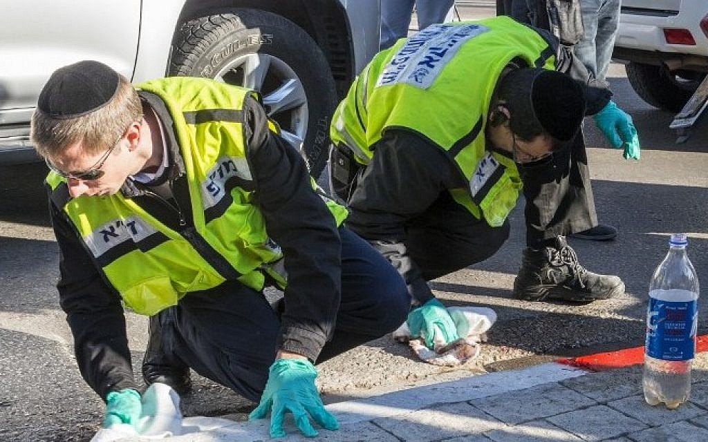 Israeli emergency services personnel clean the sidewalk at the scene of an attack after a Palestinian man stabbed several people on a Tel Aviv bus on January 21, 2015. (photo credit: AFP/JACK GUEZ)