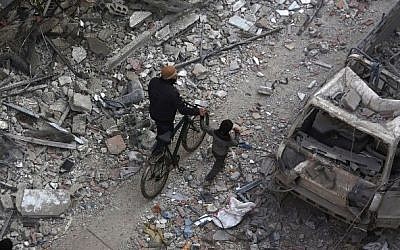 A Syrian man walks with a young boy amid debris in a rebel-held area northeast of Damascus, January 21, 2015. (photo credit: AFP/Abd Doumany)