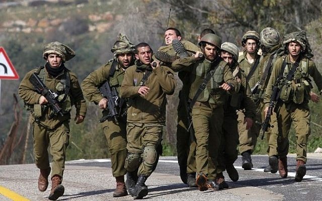 IDF soldiers carry their injured comrade after an anti-tank missile hit an army vehicle in an area on the border with Lebanon on January 28, 2015. (photo credit: Jalaa Marey/AFP) IDF soldiers carry their injured comrade after an anti-tank missile hit an army vehicle in an area on the border with Lebanon on January 28, 2015. (photo credit: Jalaa Marey/AFP)