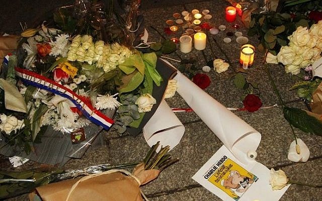 Flowers, candles and a picture of the front page of an edition of Charlie Hebdo laid out on the pavement near the offices of French satirical weekly Charlie Hebdo in Paris on January 7, 2015. (AFP/MATTHIEU ALEXANDRE)