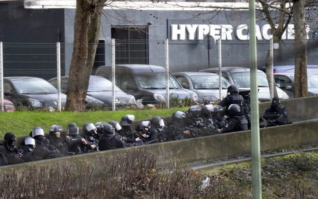 A photo taken on January 9, 2015 shows members of the French police forces taking position by the kosher grocery store in Saint-Mande, near Porte de Vincennes, eastern Paris, where a gunman opened fire at the kosher grocery store and took at least five people hostage, sources told AFP. (Photo credit: AFP / ERIC FEFERBERG)