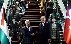 Turkish President Recep Tayyip Erdogan, right, and Palestinian President Mahmoud Abbas shake hands in front of 16 soldiers who represent the 16 Turkish states founded in the past at the presidential palace in Ankara, Turkey on January 12, 2015. (photo credit: AFP/ADEM ALTAN)