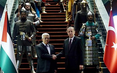 Turkish President Recep Tayyip Erdogan, right, and Palestinian President Mahmoud Abbas shake hands in front of 16 soldiers who represent the 16 Turkish states founded in the past at the presidential palace in Ankara, Turkey on January 12, 2015. (photo credit: AFP/ADEM ALTAN)