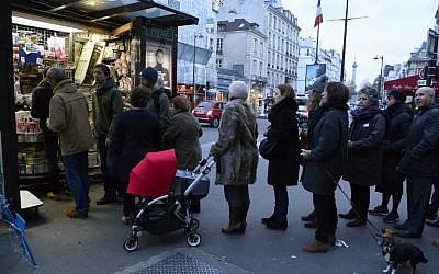 People wait outside a kiosk in Paris on January 14, 2015 as the latest edition of French satirical magazine Charlie Hebdo went on sale. (photo credit:  AFP PHOTO / BERTRAND GUAY)