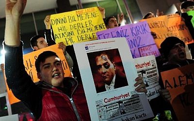 Turkish nationalists shout slogans and hold placards reading "we love our Prophet and also our leader Mustafa Kemal Ataturk" during a protest against the publication by Turkish daily newspaper Cumhuriyet of a four page pull-out containing cartoons and articles translated into Turkish from the historic Charlie Hebdo issue, on January 14, 2015 in Istanbul. The daily Cumhuriyet, which strongly opposes President Recep Tayyip Erdogan, printed a four page pull-out containing cartoons and articles from the January 14, 2015 historic Charlie Hebdo issue, along with a Charlie Hebdo editorial about how it would not give into the attacks, excerpts in Cumhuriyet including cartoons satirizing Nigerian Islamist group Boko Haram and Islamic State (IS) jihadists. (Photo credit: AFP/OZAN KOSE)