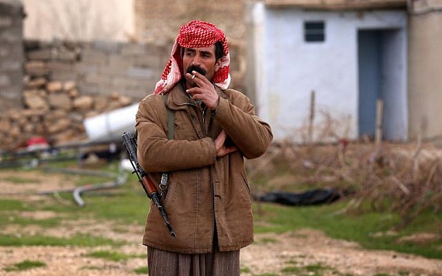An armed Yazidi man smokes a cigarette on January 15, 2015 in the village of Sinuni, in the northwestern Sinjar area, which Iraqi Kurdish forces recaptured from Islamic State group fighters. (AFP/Safin Hamed)