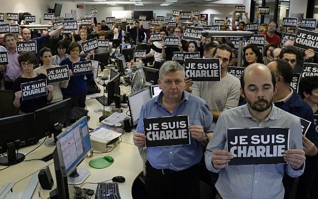 Journalists hold placard reading "I am Charlie" as they hold a minute of silence, on January 7, 2015 at the offices of French news agency Agence France Presse, following the attack by gunmen in the offices of the French satirical weekly Charlie Hebdo. (Photo credit: AFP/BERTRAND GUAY)