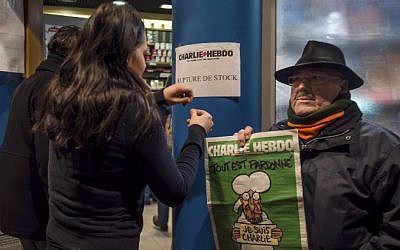 A sign which translates as "Charlie Hebdo - Sold Out" is displayed as a customer holds a copy of the magazine outside a newsagents in Dunkirk on January 14, 2015. (photo credit: AFP/PHILIPPE HUGUEN) 