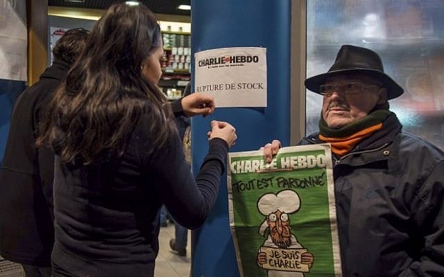 A sign which translates as "Charlie Hebdo - Sold Out" is displayed as a customer holds a copy of the magazine outside a newsagents in Dunkirk on January 14, 2015. (photo credit: AFP/PHILIPPE HUGUEN) 