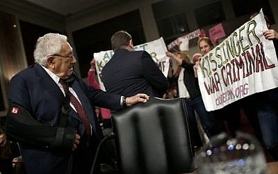 Protesters shout 'Arrest Kissinger for war crimes' as former US secretary of state Henry Kissinger (left) arrives for testimony before the Senate Armed Services Committee, in Washington, DC,  January 29, 2015. (photo credit: AFP/Win McNamee/Getty Images)