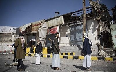 Houthi Shiite Yemeni stand guard in front of a building damaged during recent clashes near the presidential palace in Sanaa, Yemen, Tuesday, Jan. 20, 2015. (photo credit: AP Photo/Hani Mohammed)