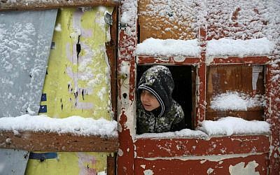 A Syrian boy looks out through his tent door covered in snow at a refugee camp in Deir Zannoun village, in the Bekaa valley, east Lebanon, Wednesday, Jan. 7, 2015. (AP Photo/Hussein Malla)