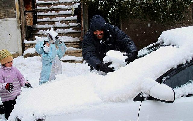 People play with snow accumulated on a vehicle in Damascus, Syria, Wednesday, Jan. 7, 2015. (AP Photo)
