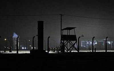 People walk holding lit candles past guard towers next to the railway leading to the Birkenau Nazi death camp in Oswiecim, Poland, Tuesday, Jan. 27, 2015, after the official remembrance ceremony. About 300 survivors gathered with leaders from around the world to remember the 1.1 million people killed at Auschwitz-Birkenau and the millions of others killed in the Holocaust. (photo credit: AP Photo/Alik Keplicz)