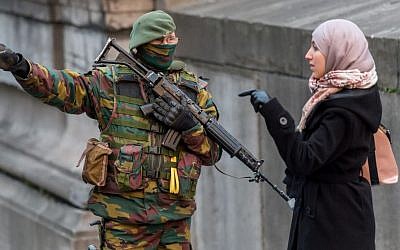 A Belgian security officer talks with a woman as he patrols near the Palace of Justice, where suspects wanted in Belgium on terrorism-related charges were set to appear before the federal court, in Brussels,, January 21, 2015. (photo credit: AP/Geert Vanden Wijngaert)