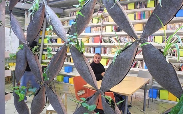 A man sits in the free lending library at the Central Bus Station, which has books in 12 languages and operates on an honor system. (photo credit: Melanie Lidman/Times of Israel)