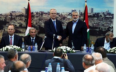 Palestinian Prime Minister Rami Hamdallah shakes hands with senior Hamas leader Ismail Haniyeh, at Haniyeh's house in Gaza city on October 9, 2014