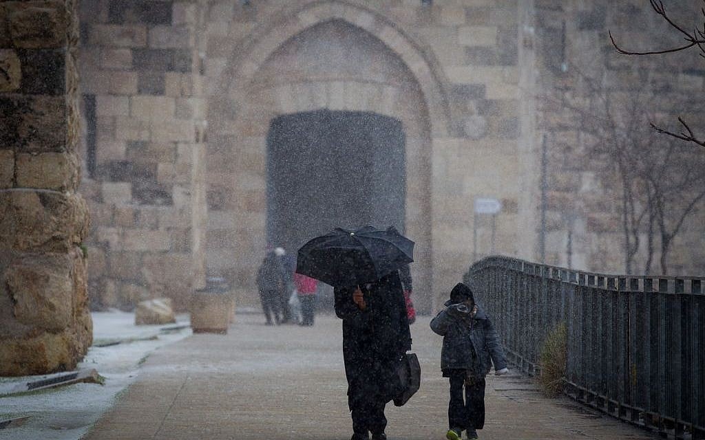 People seen walking by the walls of Jerusalem's Old City Walls as snow begins to fall, Wednesday, January 7, 2015 (photo credit: Miriam Alster/FLASH90)