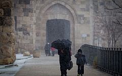 People seen walking by the walls of Jerusalem's Old City Walls as snow begins to fall, Wednesday, January 7, 2015 (photo credit: Miriam Alster/FLASH90)