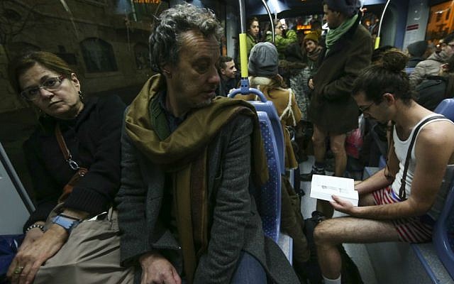 Argentinian tourist Esteban glances at pantless commuters on Jerusalem's light rail. No Pants Train Ride, January 11, 2015. (Nati Shohat/Flash 90)
