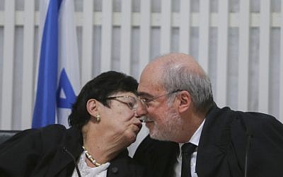 Supreme Court Justice Miriam Naor (left) embraces outgoing Supreme Court President Asher Grunis on January 15, 2015. (photo credit: Alex Kolomoisky/POOL)