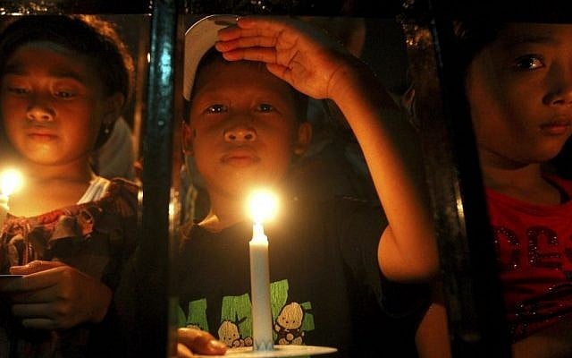Indonesian children hold candles to pray for the victims of AirAsia Flight 8501 in Surabaya, Indonesia, Wednesday, Dec. 31, 2014. (Photo credit: AP/Firdia Lisnawati)
