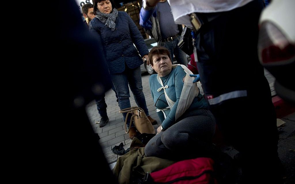 Israeli paramedics treat an injured woman at the scene of a stabbing attack in Tel Aviv on January 21, 2015. (photo credit: AP/Oded Balilty)