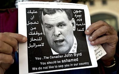 A Palestinian protester holds a poster with a photo of Canadian Foreign Minister John Baird that reads in Arabic, "You should be ashamed of your biased position towards Israel," during Baird's meeting with Palestinian Authority Foreign Minister Riad Maliki, in the West Bank city of Ramallah, Sunday, Jan. 18, 2015. Dozens of Palestinian protesters have hurled eggs and shoes at the convoy of the visiting Canadian foreign minister. (photo credit: AP Photo/Nasser Nasser)