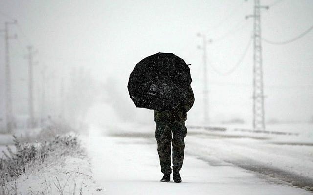 A Lebanese army soldier holds an umbrella as he walks at a main road covered by the snow, in Al-Marj village, in the Bekaa valley, east Lebanon, Wednesday, Jan. 7, 2015. (AP Photo/Hussein Malla)