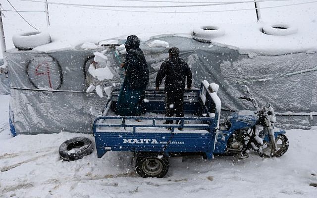 A Syrian woman and her son remove the snow from the top of their tent at a refugee camp in Deir Zannoun village, in the Bekaa valley, east Lebanon, Wednesday, Jan. 7, 2015. (Photo credit: AP/Hussein Malla) A Syrian woman and her son remove the snow from the top of their tent at a refugee camp in Deir Zannoun village, in the Bekaa valley, east Lebanon, Wednesday, Jan. 7, 2015. (Photo credit: AP/Hussein Malla)