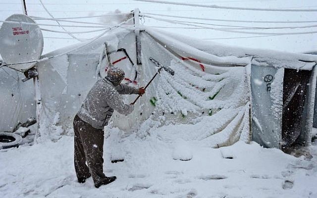 A Syrian man removes the snow from his tent at a refugee camp in Deir Zannoun village, in the Bekaa valley, east Lebanon, Wednesday, Jan. 7, 2015. (AP Photo/Hussein Malla)