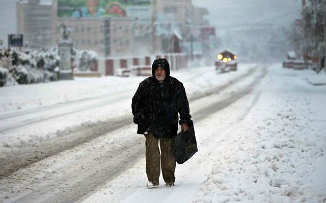 A Lebanese man walks on main road covered by the snow, in Chtoura town, in the Bekaa valley, east Lebanon, Wednesday, Jan. 7, 2015. (AP Photo/Hussein Malla)