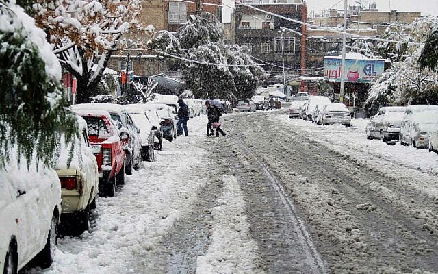 People walk across a snow-blanketed street in Damascus, Syria, Wednesday, Jan. 7, 2015. (AP Photo)