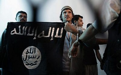 In this Tuesday, April 23, 2013 file photo, a suspected Yemeni al-Qaeda militant, center, holds an Islamist banner as he stands behind bars during a court hearing in state security court in Sanaa, Yemen. Arabic on flag reads, "There is no God but Allah and Mohammed is the messenger of God." (Photo credit: AP /Hani Mohammed)