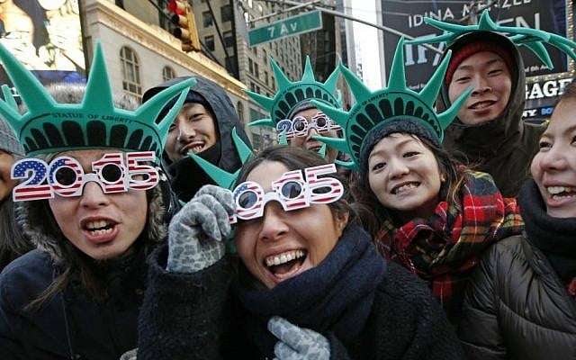 Tourists Teru Udaka, left, and Yuko Yamakata, wearing 2015 glasses, join other friends from Osaka, Japan to celebrate New Year's Eve in Times Square hours before the start of the celebration in New York, Wednesday, Dec. 31, 2014. (Photo credit: AP/Kathy Willens)