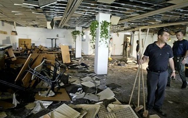 Workers clean the inside of a cafeteria on July 31, 2002, hours after a bomb exploded at Hebrew University in Jerusalem, killing nine, four of them Americans, and wounding more than 70. (AP Photo/David Guttenfelder)