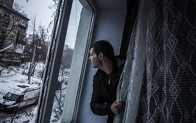 Alexander, 35, looks through a broken window of his flat, hit by Ukrainian Army Artillery, in the Voroshilovsky area, center of Donetsk, Ukraine. Sunday, Jan. 18, 2015. (photo credit: AP Photo/Manu Brabo)