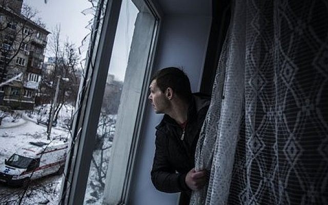 Alexander, 35, looks through a broken window of his flat, hit by Ukrainian Army Artillery, in the Voroshilovsky area, center of Donetsk, Ukraine. Sunday, Jan. 18, 2015. (photo credit: AP Photo/Manu Brabo) Alexander, 35, looks through a broken window of his flat, hit by Ukrainian Army Artillery, in the Voroshilovsky area, center of Donetsk, Ukraine. Sunday, Jan. 18, 2015. (photo credit: AP Photo/Manu Brabo)