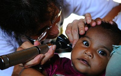 A US Navy doctor checks a infant for an ear infection during an exam at a medical clinic. (Illustrative photo credit: Courtesy US Navy/Joshua Adam Nuzzo)