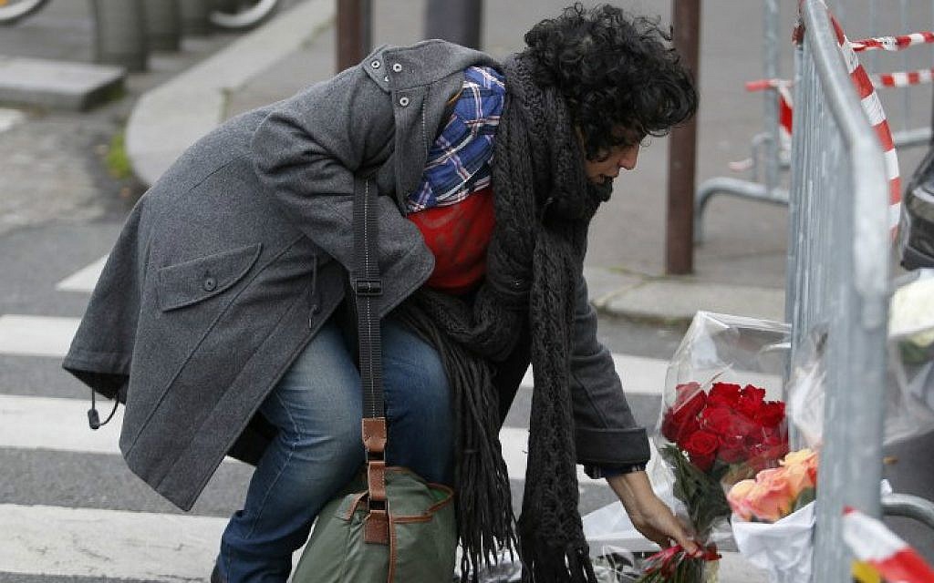 A woman lays flowers near a kosher grocery store in Porte de Vincennes, eastern Paris, on January 10, 2015 (photo credit: AFP/ KENZO TRIBOUILLARD)