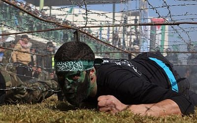 Palestinian youth crawls under a barbed wire obstacle during a graduation ceremony for a training camp run by the Hamas movement on January 29, 2015 in Khan Yunis, in the southern Gaza Strip. Photot credit: AFP/ SAID KHATIB)