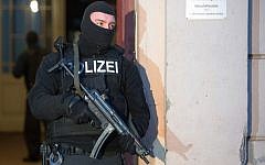 Illustrative: A member of a police task force stands in front of an apartment building where raids took place against suspected jihadists on January 16, 2015 in Berlin (photo credit: AFP/ LUKAS SCHULZE)