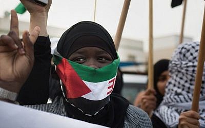 A Bedouin woman, covering her face with a Palestinian flag, marches with fellow protesters ahead of the funeral of Sami al-Zayadna, 47, in the southern Israeli Bedouin city of Rahat on January 19, 2015. Zayadna died the previous day following clashes with Israeli policemen during the funeral of Sami al-Ajar, 22, another Bedouin who died of a gunshot wound last week during a police drug raid on the Negev Bedouin town. (Photo credit: AFP/MENAHEM KAHANA)